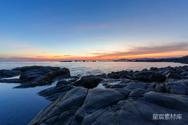 夕阳西下，海平面上有岩石作为前景。