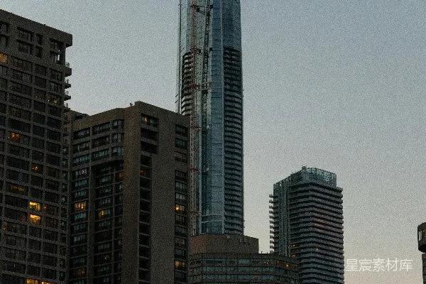 正在建设中的高耸大楼旁边有起重机，背景是城市里的建筑物。