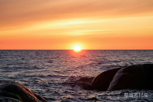 夕阳西下，海平线前岩石耸立。