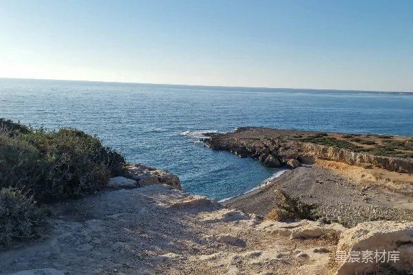 岩石海岸旁有平静的蓝海水和晴朗的天空。