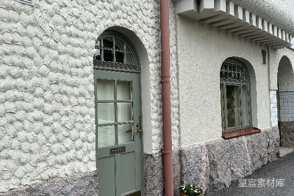 一座带有绿色门和窗的白色建筑