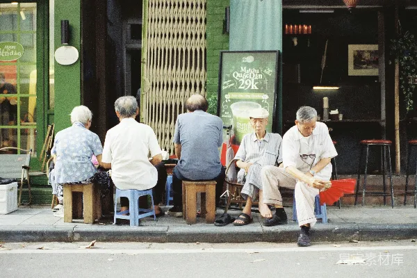 老年人坐在商店外面的凳子上。