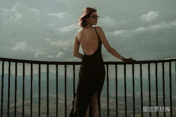黑色连衣裙的女人看着一道栅栏
