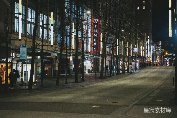 城市夜景中的街道，有灯光照亮的建筑物和树木。