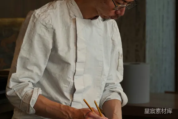 一名白制服厨师正在用筷子准备食物。