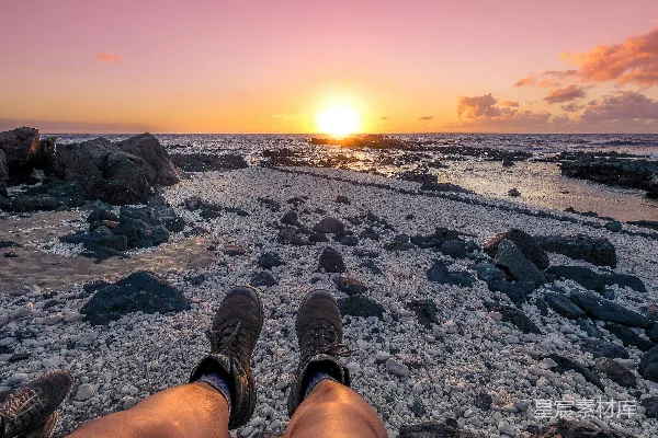穿着棕色裤子的坐着的人俯瞰海景，在黄金时刻。