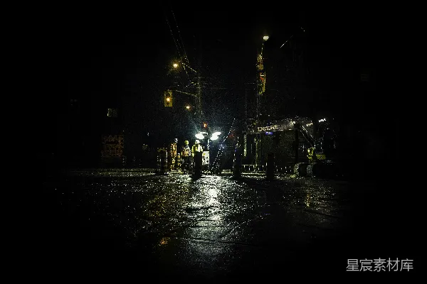 三个人在夜间路灯亮起的地方靠近电线杆站立。