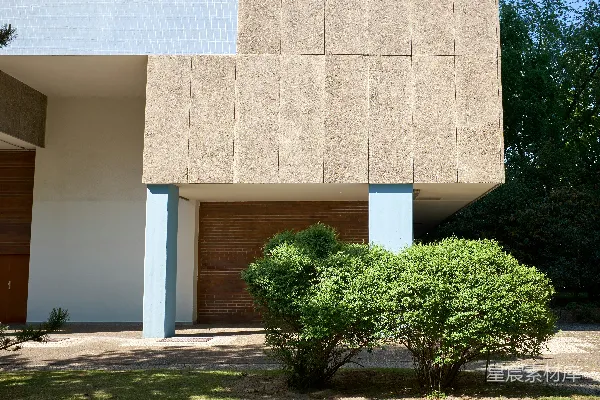 前面有一栋建筑，周围有树木和灌木丛。
