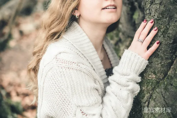 高清摄影 戴着眼镜的女人靠在一棵树上。