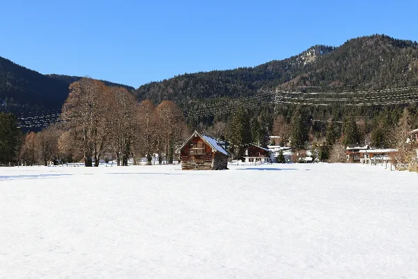 背景有一座房子的覆盖着白雪的田野