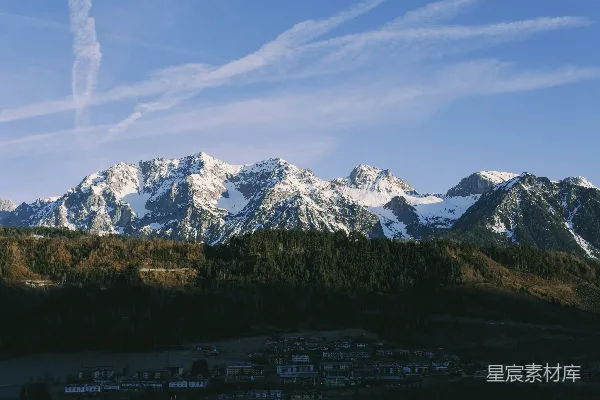 雪山耸立在深林之上，蓝天作背景。