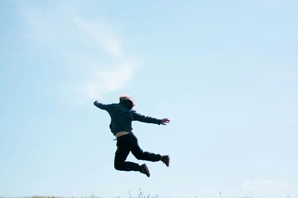 黑夹克男人在白天绿色草地的田野上跳跃