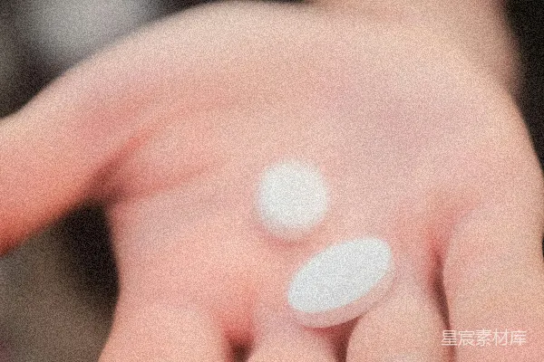 手中拿着两片药的人