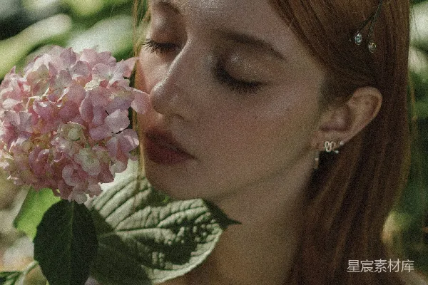 一个女人闭上眼睛闻一朵花的香味。