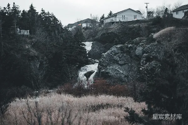 远处一座山坡上的房屋后面有一道瀑布的景象