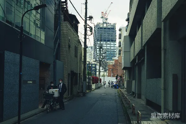 狭窄的小巷，远处有建筑和施工场地。