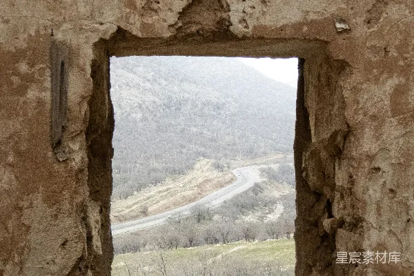 山间蜿蜒小路旁旧窗所见之景。