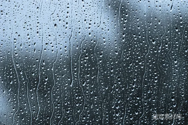 高清摄影 雨滴落在窗户上，背景中有一座建筑物。