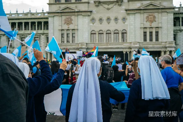 身穿蓝白衣服的人在白色混凝土建筑附近白天站立