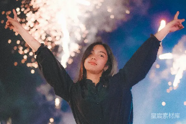 穿着黑领口长袖衬衫和蓝色牛仔短裤的女士做出和平手势，站在一群人中间看着烟火表演时