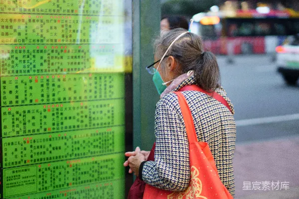 一个戴着口罩的女人站在绿色的围栏旁边。