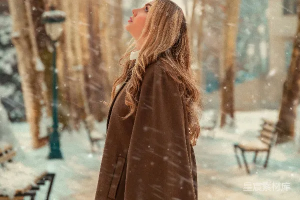 一个穿着棕色外套的女人在雪地中行走。