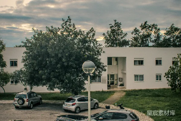 停在一座白色建筑外面的停车场里的汽车。