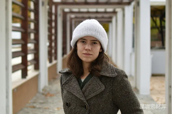 灰衣女子戴着灰色针织帽穿着灰色大衣站在灰色混凝土人行道上白天