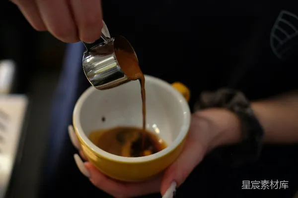 一个人将咖啡倒入一个黄色的杯子里。