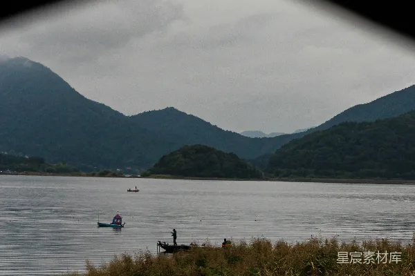 湖面上静谧的船只，远处有朦胧的山峦。