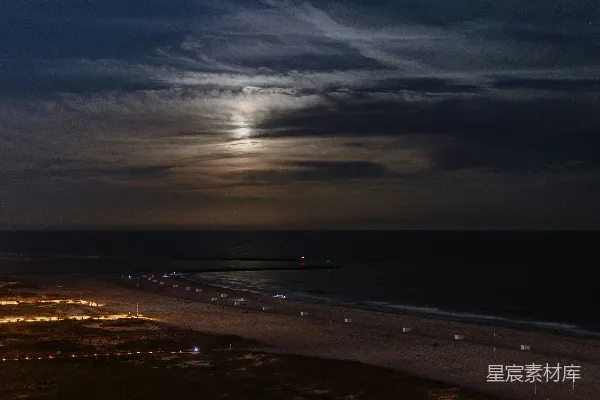 夜晚月亮圆润照亮一片海滩。