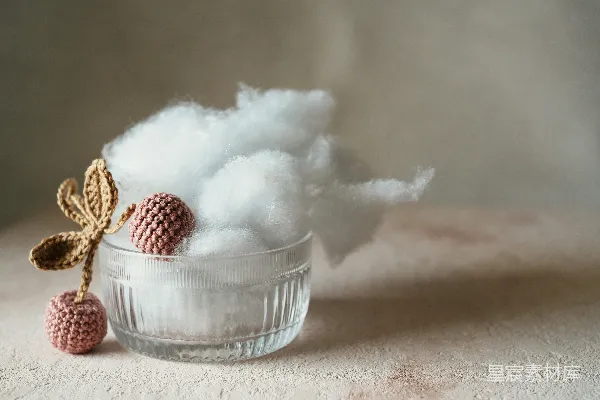 一个装有棉花的玻璃碗旁边放着一个小绒球