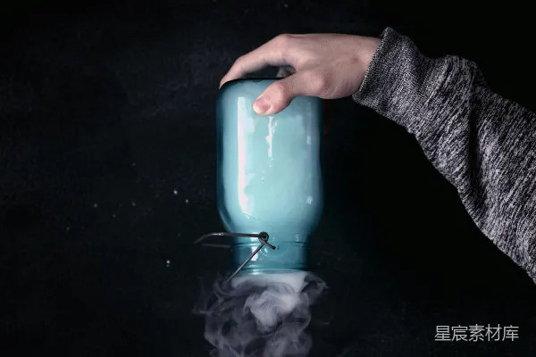 手持透明玻璃罐的人