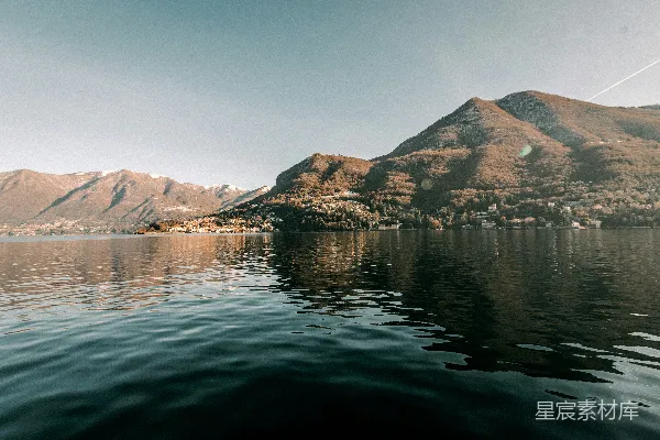 平静的湖水倒映着山景和一个小城镇。