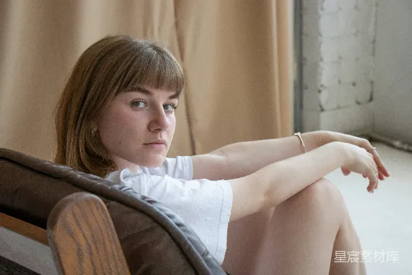 白色T恤女子坐在棕色木椅上