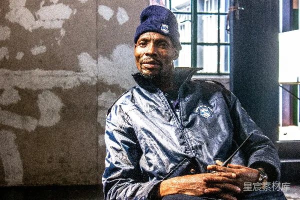 一个戴蓝色帽子的男人在坐着。