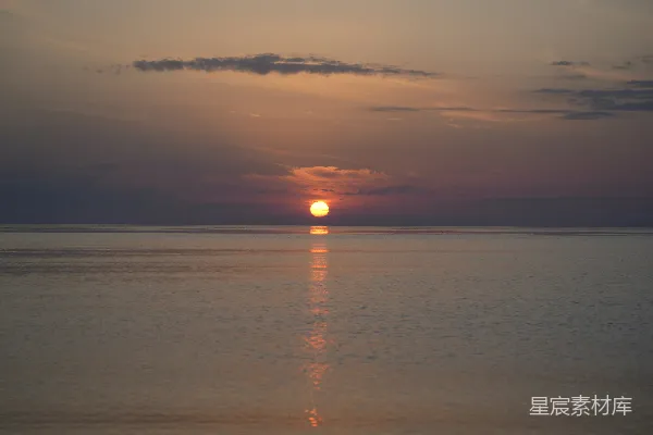 一湾平静的海水中美丽的日落与太阳倒影。