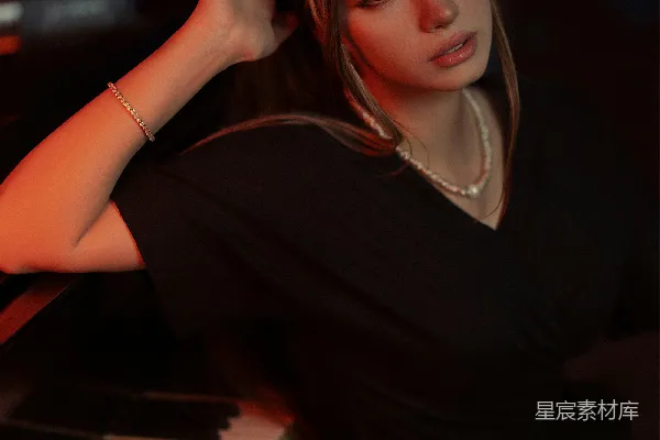 一位女性坐在钢琴旁摆姿势拍照。
