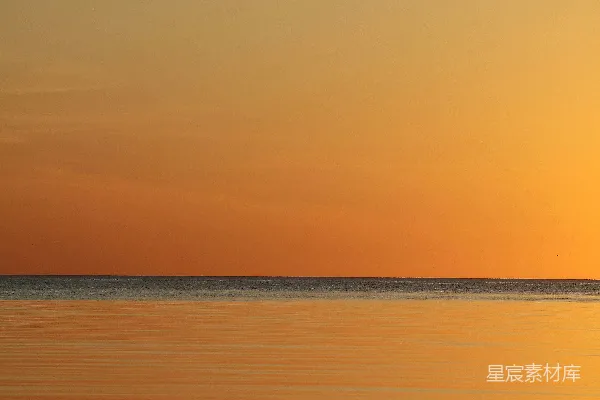 夕阳下的橙色天空中平静的海面