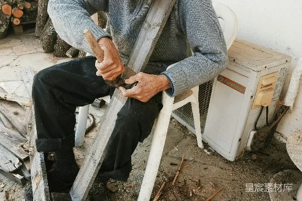 一个男人坐在椅子上，手中拿着一块木头。