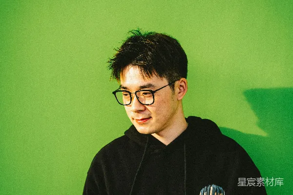 戴着眼镜的男人站在一丛绿色植物前