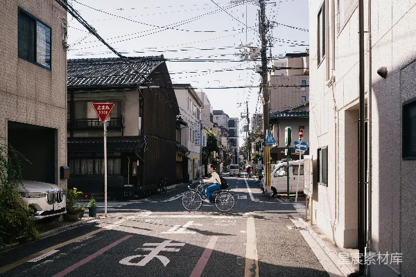 一个男人骑自行车在高大建筑旁边的一条街道上前行