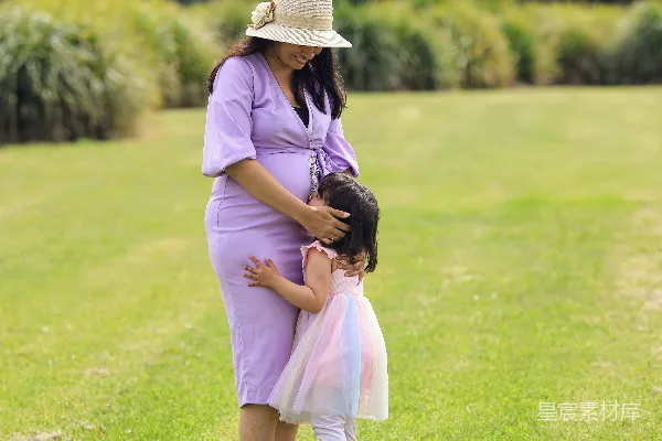 怀孕的女人拥抱着她的幼子。