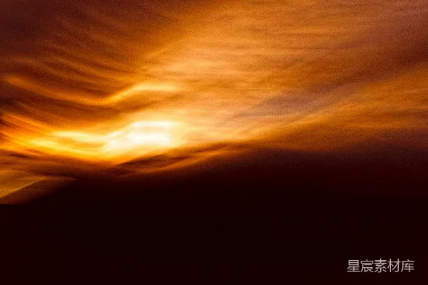一幅模糊的夕阳照片，背景中有云朵。