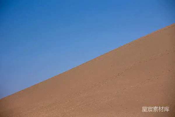 一片广阔的沙漠沙丘在蓝天的映衬下。