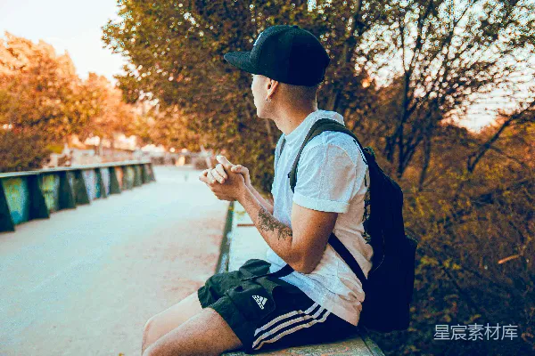 一个男人坐在长凳上，看着他的手机。