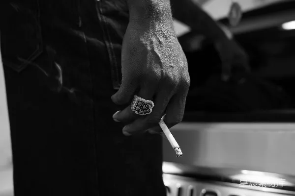 一个男子拿着香烟靠近一辆车。