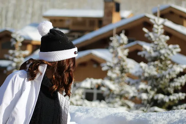 穿着黑白夹克的女人站在覆盖着白雪的地面上，在白天。
