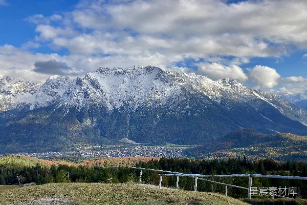 白天绿色草地旁雪覆盖的山峰附近
