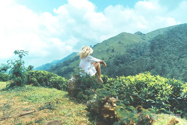 女人坐在山峦之间的岩石上